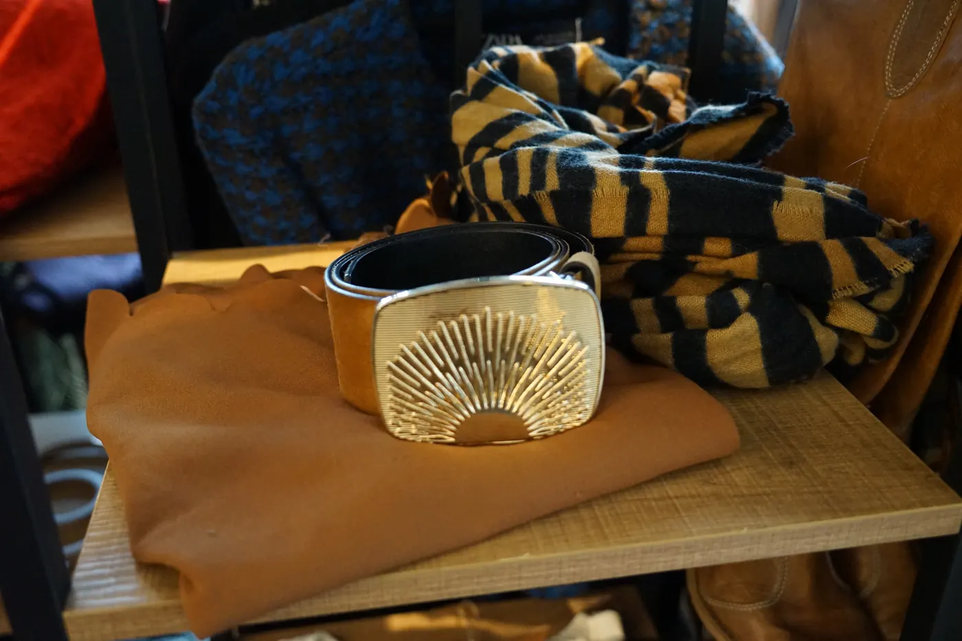 Goldener Gürtel mit Sonnenschnalle auf Wildleder und gestreiftem Schal