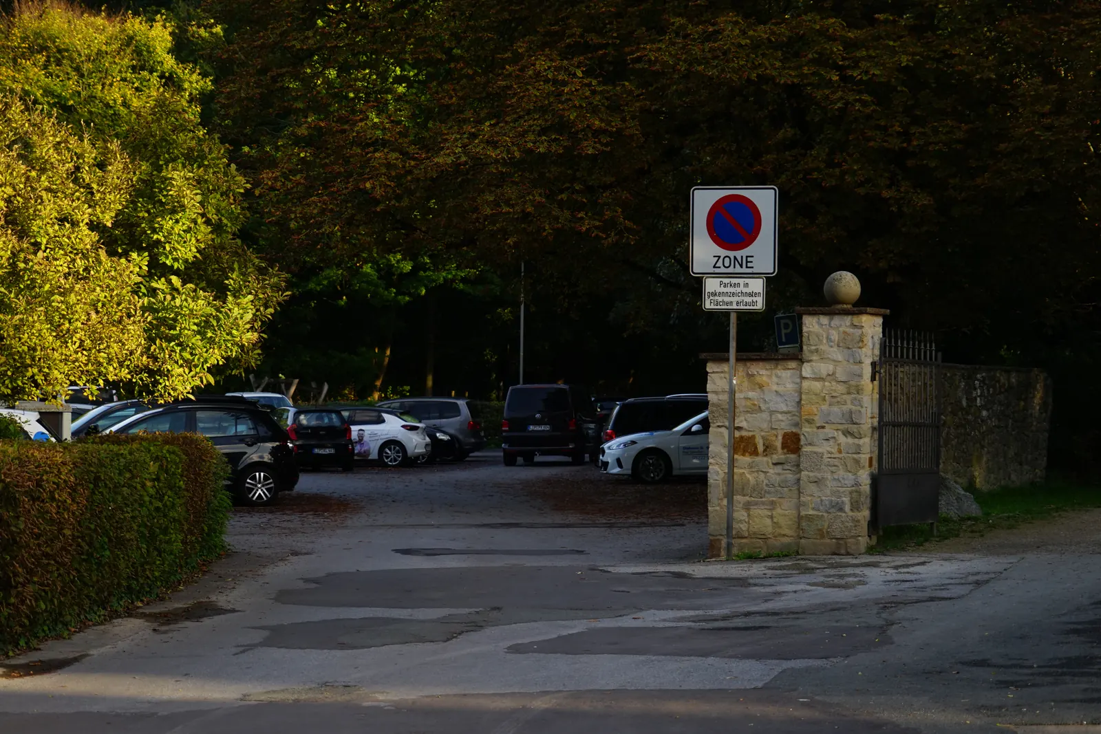 Parkplatz am Schlosspark mit Natursteinpfeilern und Parkschild