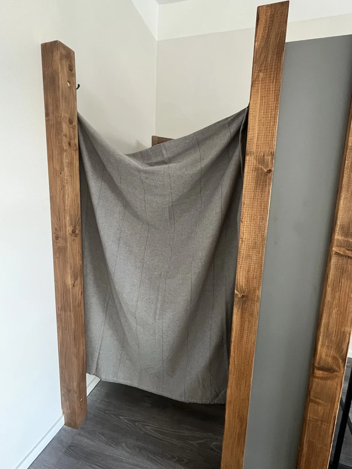 Umkleidekabine mit grauem Vorhang zwischen Holzpfosten